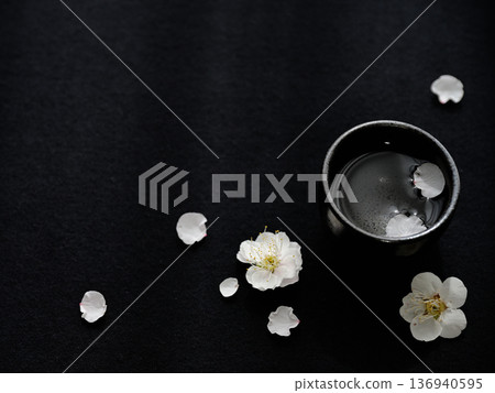 Plum blossoms and sake cups on a black background - Japanese spring design with space Plum blossoms and sake cups on a black background - Japanese spring design with space 136940595