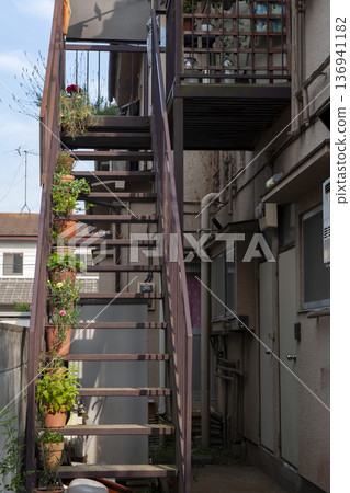 Flower pots displayed on the exterior stairs of an apartment Flower pots displayed on the exterior stairs of an apartment 136941182