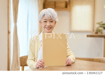 Smiling senior Asian woman holding a yellow file Smiling senior Asian woman holding a yellow file 136942127