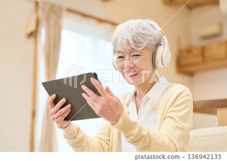 Asian senior woman watching drama on tablet Asian senior woman watching drama on tablet 136942135