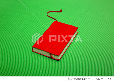 Red notebook with a bookmark on a green background 136942233