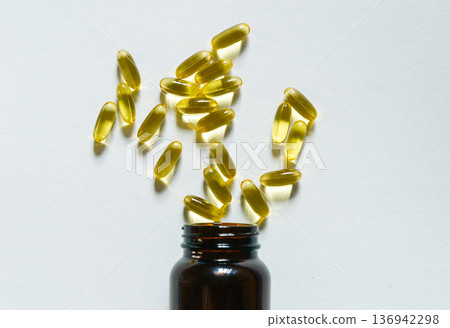 Omega 3 fish oil capsules spilling from a bottle on white background. Health concept Omega 3 fish oil capsules spilling from a bottle on white background. Health concept 136942298