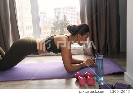 Close Up of a Beautiful Fitness Girl in an Athletic Top Doing Push Up Exercises. Woman Training at Home in Living Room Close Up of a Beautiful Fitness Girl in an Athletic Top Doing Push Up Exercises. Woman Training at Home in Living Room 136942643