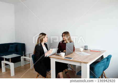 Women hold meeting in modern office while discussing project details during working hours Women hold meeting in modern office while discussing project details during working hours 136942920