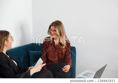 Women have a discussion in an office setting during a business meeting about work topics and tasks Women have a discussion in an office setting during a business meeting about work topics and tasks 136942931