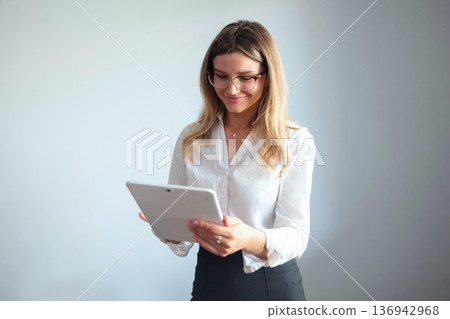 Woman using a tablet in a business office setting during working hours 136942968