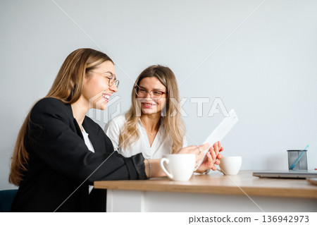 Women discuss work matters at an office table during a business meeting in the afternoon 136942973