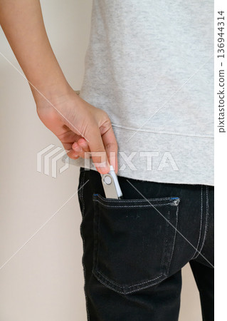 A person carrying a cryptocurrency wallet in their pocket 136944314