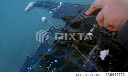 An unidentified hand cleans the car window from ice. An unidentified hand cleans the car window from ice. 136945152