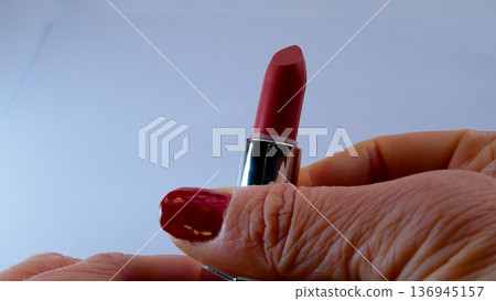 A woman's hand opens the red lipstick and unwinds it. A woman's hand opens the red lipstick and unwinds it. 136945157