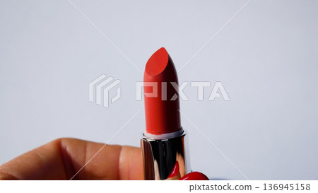 A woman's hand opens the red lipstick and unwinds it.  136945158