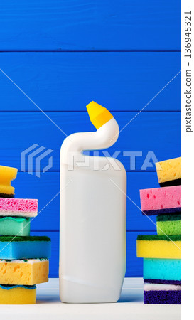 Cleaning supplies and sponges are set against a bright blue wooden background 136945321