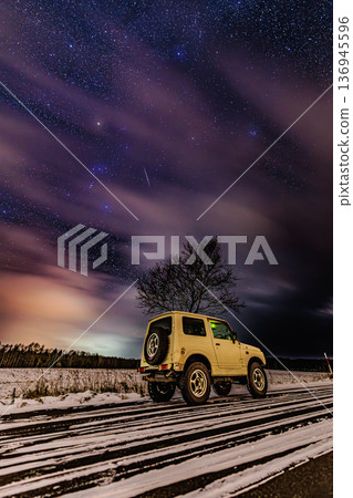 A night with an off-road car shining against the starry sky and snowy scenery 136945596