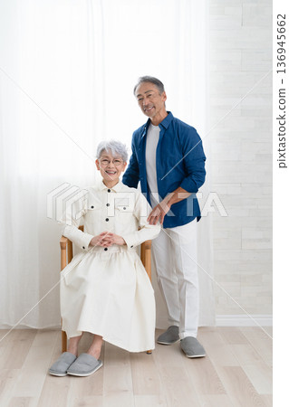 A woman sitting on a chair and a man standing next to her. Lifestyle image A woman sitting on a chair and a man standing next to her. Lifestyle image 136945662