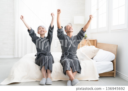 Senior couple sitting on the bed in a gown coat Lifestyle image Senior couple sitting on the bed in a gown coat Lifestyle image 136945692