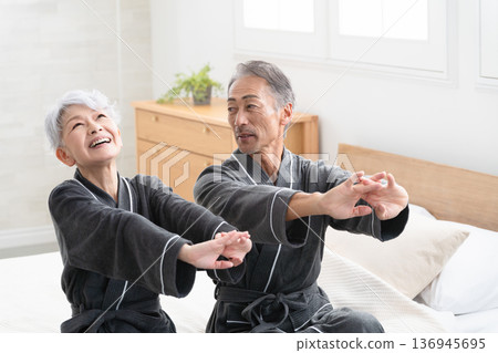 Senior couple sitting on the bed in a gown coat Lifestyle image Senior couple sitting on the bed in a gown coat Lifestyle image 136945695
