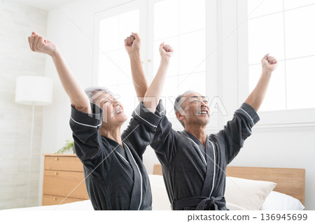 Senior couple sitting on the bed in a gown coat Lifestyle image Senior couple sitting on the bed in a gown coat Lifestyle image 136945699