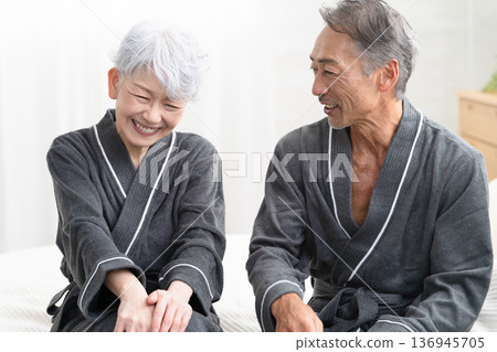 Senior couple sitting on the bed in a gown coat Lifestyle image Senior couple sitting on the bed in a gown coat Lifestyle image 136945705