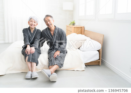 Senior couple sitting on the bed in a gown coat Lifestyle image Senior couple sitting on the bed in a gown coat Lifestyle image 136945706