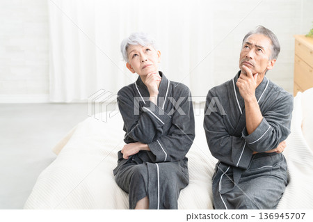 Senior couple sitting on the bed in a gown coat Lifestyle image Senior couple sitting on the bed in a gown coat Lifestyle image 136945707