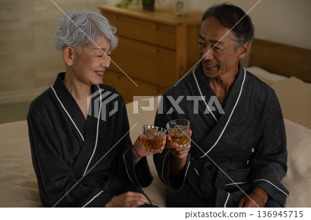 Senior couple sitting on the bed in a gown coat Lifestyle image Senior couple sitting on the bed in a gown coat Lifestyle image 136945715