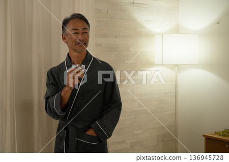 Senior man wearing a gown and holding a rocks glass Lifestyle image Senior man wearing a gown and holding a rocks glass Lifestyle image 136945728