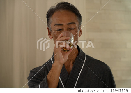 Senior man wearing a gown and holding a rocks glass Lifestyle image Senior man wearing a gown and holding a rocks glass Lifestyle image 136945729