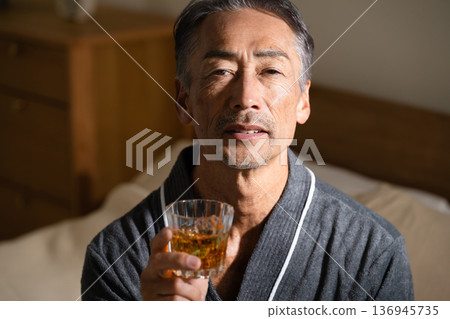 Senior man wearing a gown and holding a rocks glass Lifestyle image Senior man wearing a gown and holding a rocks glass Lifestyle image 136945735