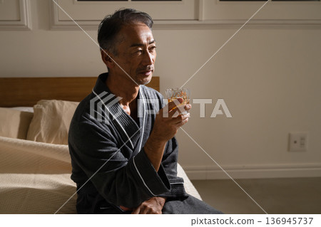 Senior man wearing a gown and holding a rocks glass Lifestyle image Senior man wearing a gown and holding a rocks glass Lifestyle image 136945737