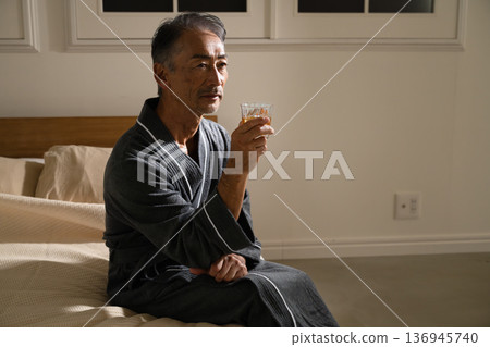 Senior man wearing a gown and holding a rocks glass Lifestyle image Senior man wearing a gown and holding a rocks glass Lifestyle image 136945740