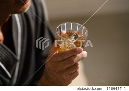 Senior man wearing a gown and holding a rocks glass Lifestyle image Senior man wearing a gown and holding a rocks glass Lifestyle image 136945741