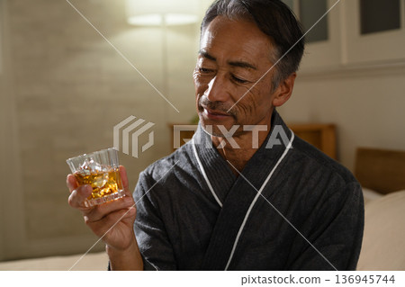 Senior man wearing a gown and holding a rocks glass Lifestyle image Senior man wearing a gown and holding a rocks glass Lifestyle image 136945744