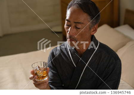 Senior man wearing a gown and holding a rocks glass Lifestyle image Senior man wearing a gown and holding a rocks glass Lifestyle image 136945746