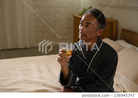 Senior man wearing a gown and holding a rocks glass Lifestyle image Senior man wearing a gown and holding a rocks glass Lifestyle image 136945747