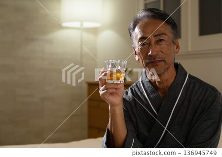 Senior man wearing a gown and holding a rocks glass Lifestyle image Senior man wearing a gown and holding a rocks glass Lifestyle image 136945749