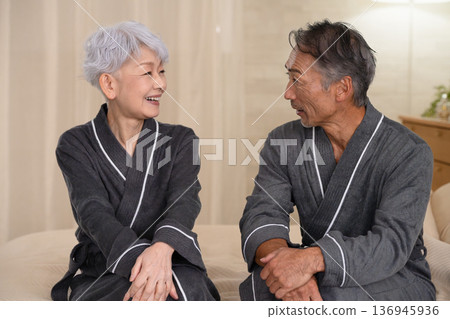 Senior couple sitting on the bed in a gown coat Lifestyle image Senior couple sitting on the bed in a gown coat Lifestyle image 136945936