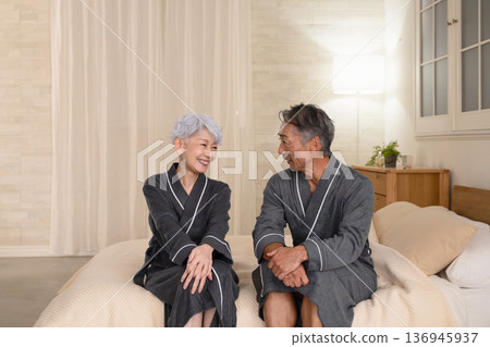 Senior couple sitting on the bed in a gown coat Lifestyle image Senior couple sitting on the bed in a gown coat Lifestyle image 136945937