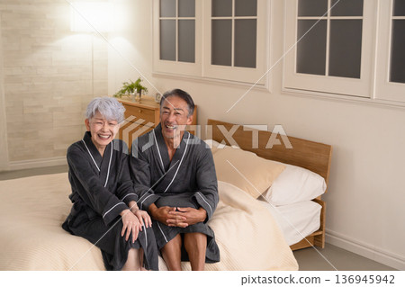 一對老年夫婦穿著長袍坐在床上,生活方式圖片 一對老年夫婦穿著長袍坐在床上,生活方式圖片 136945942