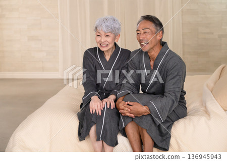 一對老年夫婦穿著長袍坐在床上,生活方式圖片 一對老年夫婦穿著長袍坐在床上,生活方式圖片 136945943