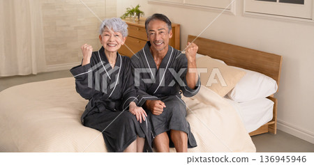 一對老年夫婦穿著長袍坐在床上,生活方式圖片 一對老年夫婦穿著長袍坐在床上,生活方式圖片 136945946