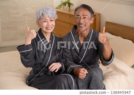 Senior couple sitting on the bed in a gown coat Lifestyle image Senior couple sitting on the bed in a gown coat Lifestyle image 136945947