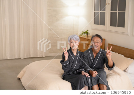 Senior couple sitting on the bed in a gown coat Lifestyle image Senior couple sitting on the bed in a gown coat Lifestyle image 136945950