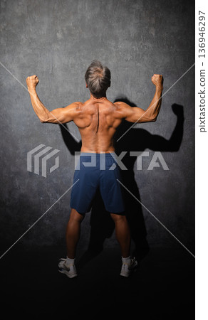 一位老年男子赤裸上身,擺出健美姿勢。運動圖片 一位老年男子赤裸上身,擺出健美姿勢。運動圖片 136946297