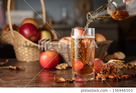 Apple cider is poured from a bottle into a glass. Apple cider is poured from a bottle into a glass. 136946503