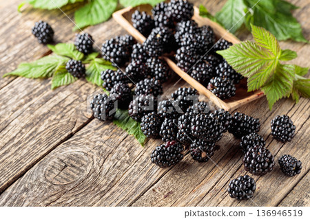 Ripe juicy blackberries with leaves on a wooden table. 136946519