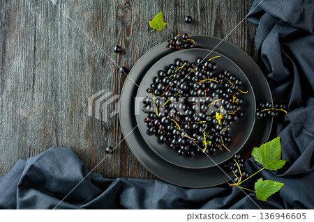 Black currant with leaves on a old wooden table. 136946605