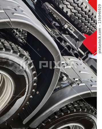 Close view of truck wheel and fender showing details of design and structure in bright light at a transport facility 136946929
