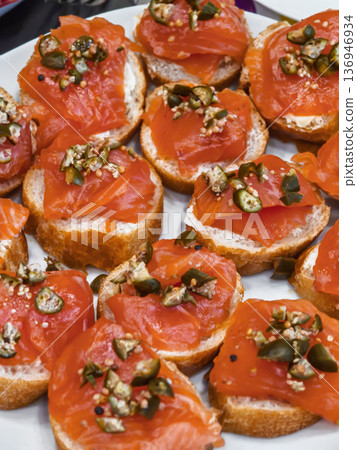 Platter of salmon bites with toppings served on bread at a gathering in a home kitchen Platter of salmon bites with toppings served on bread at a gathering in a home kitchen 136946934