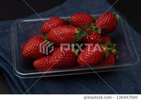 Strawberries arranged on a clear plastic tray. A dark image against a black background. Strawberries arranged on a clear plastic tray. A dark image against a black background. 136947000