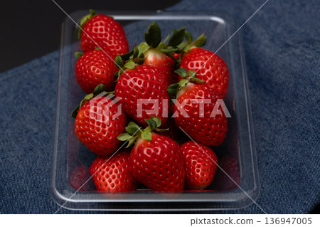 草莓擺放在透明塑膠托盤上。深色影像映襯著黑色背景。 草莓擺放在透明塑膠托盤上。深色影像映襯著黑色背景。 136947005
